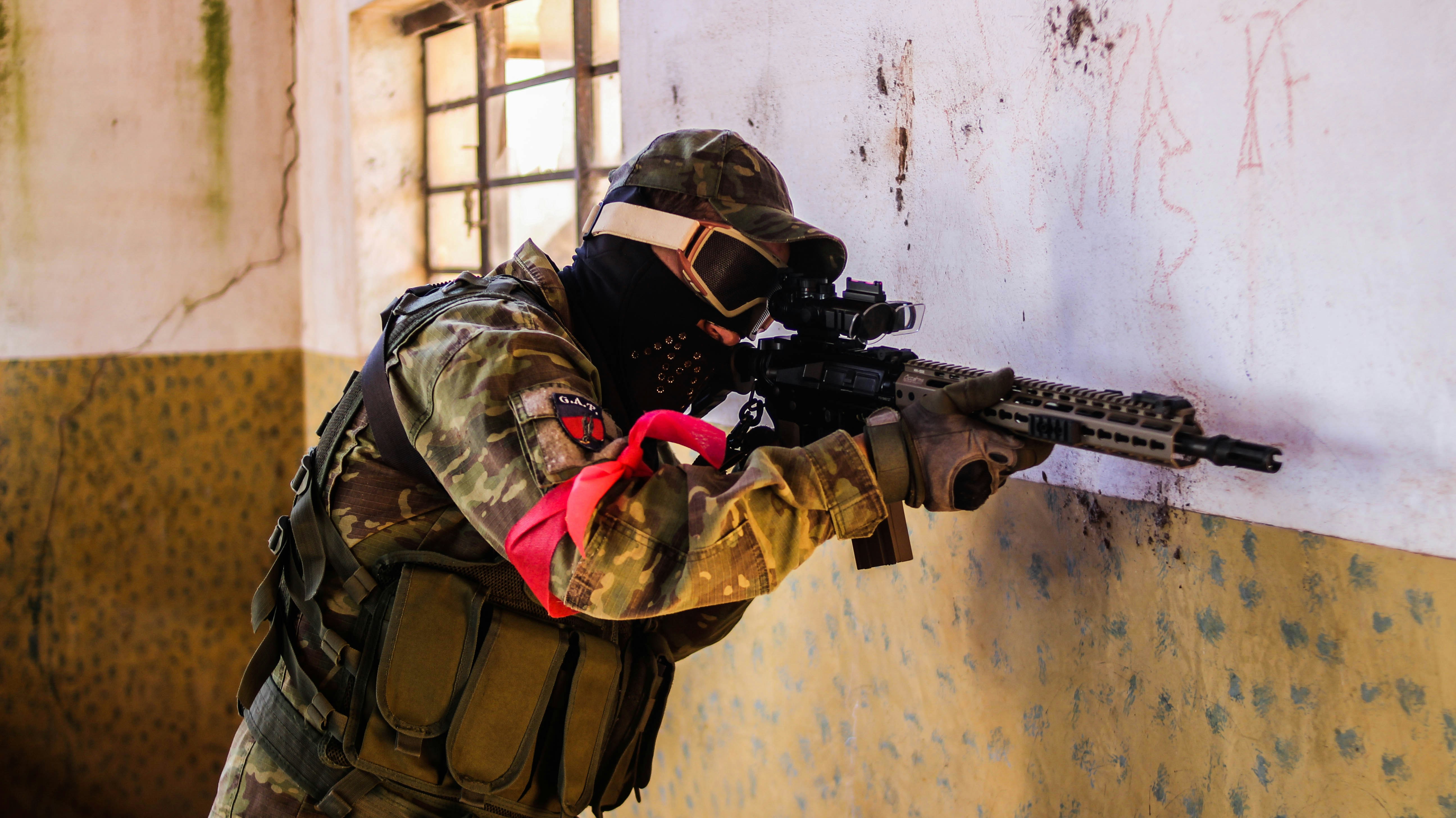 man in brown and black camouflage jacket holding black rifle
