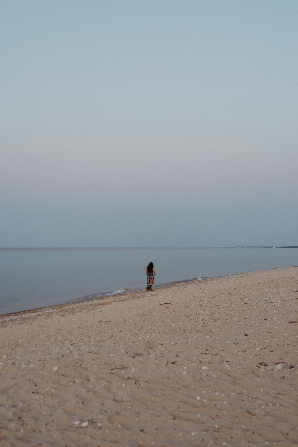 person walking on brown sand beach during daytime