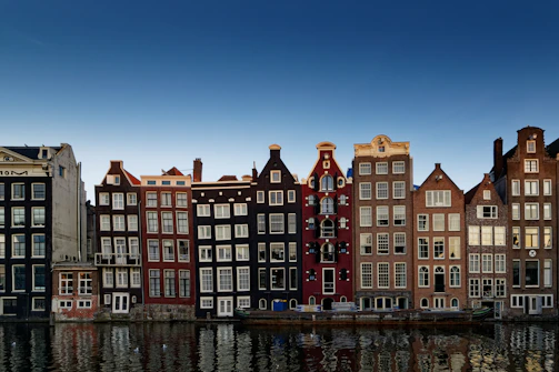 Colorful houses lining a canal in Amsterdam at dusk.