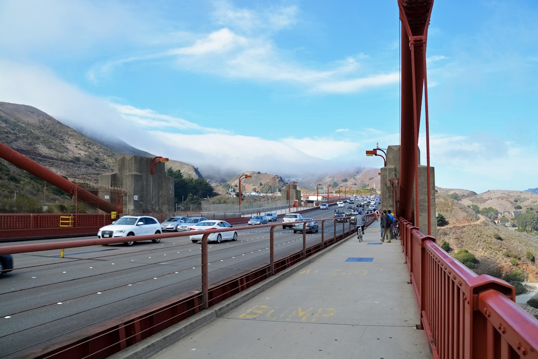 cars parked on sidewalk near bridge during daytime