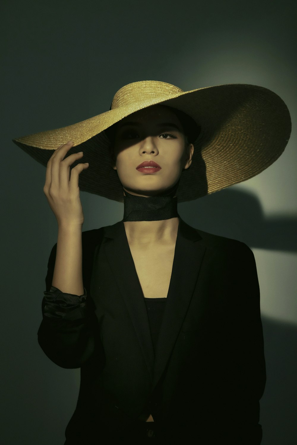 Femme en blazer noir portant un chapeau de paille marron