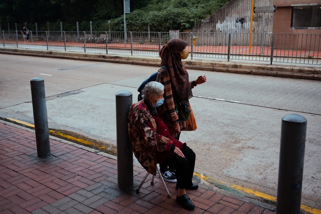 woman in brown leather jacket and black pants sitting on black steel bench during daytime