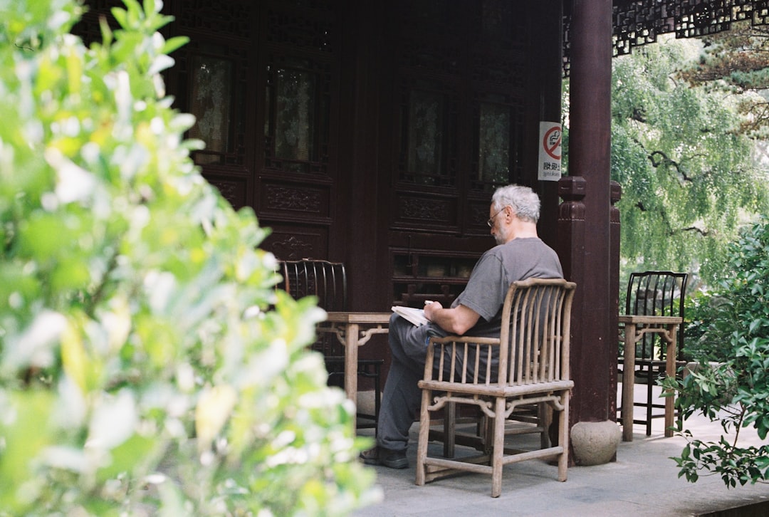 man in black long sleeve shirt sitting on brown wooden armchair