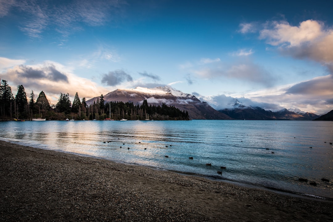 body of water near mountain under blue sky during daytime