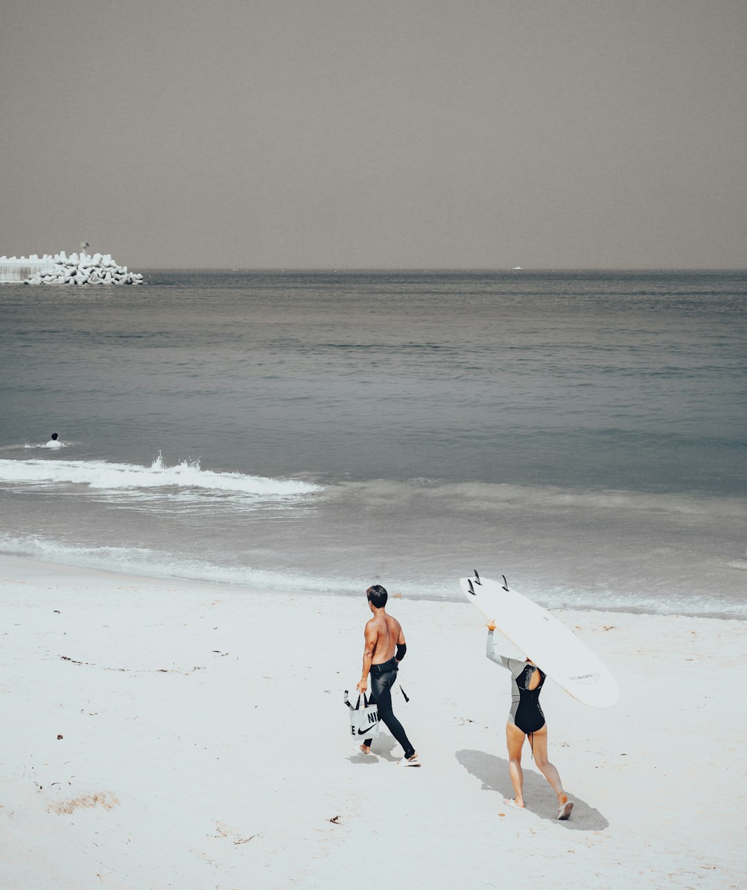 woman in white shirt and black shorts walking on beach during daytime