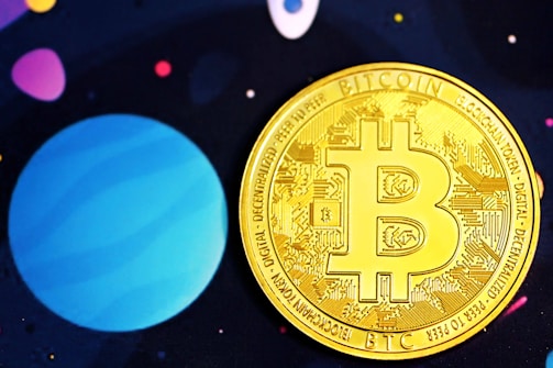 A golden Bitcoin coin adorned with intricate circuit designs is prominently placed against a background that is reminiscent of outer space, featuring large planet-like shapes in shades of blue and purple and small scattered dots in various colors.