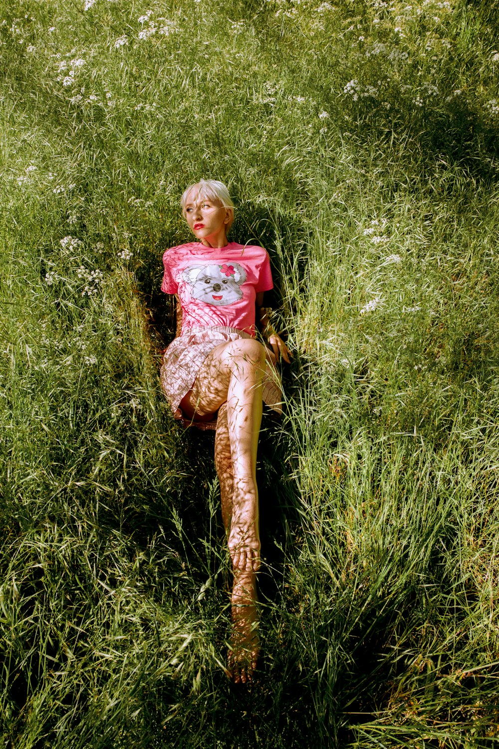 woman in red and white floral dress sitting on green grass during daytime