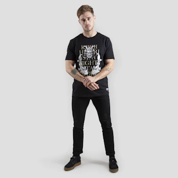 Model wearing a black minimalist t-shirt with a bold faith-inspired graphic, standing against an urban backdrop.