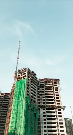 High-rise building under construction with scaffolding and safety nets visible.