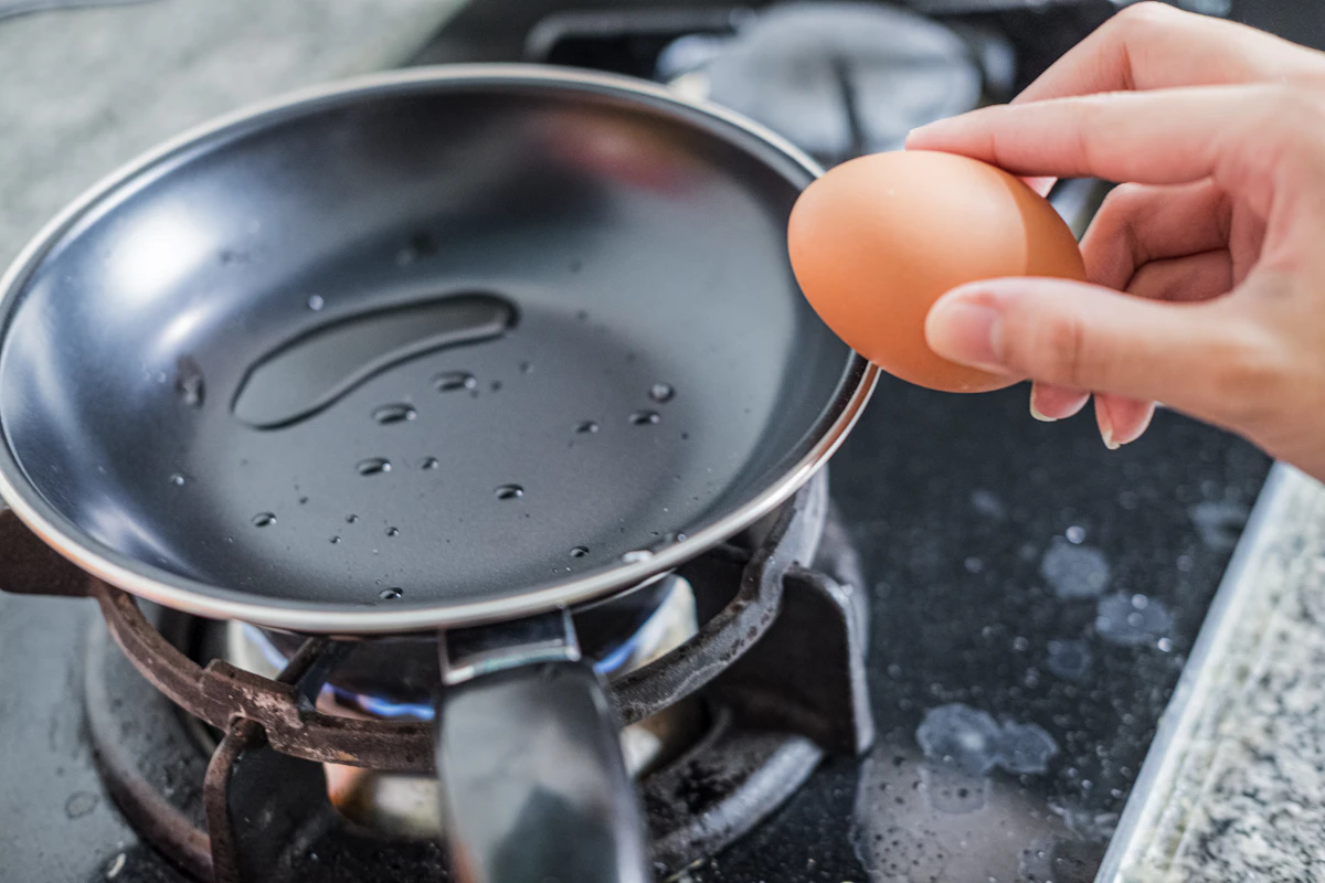 A person cooking with a black frying pan in a kitchen