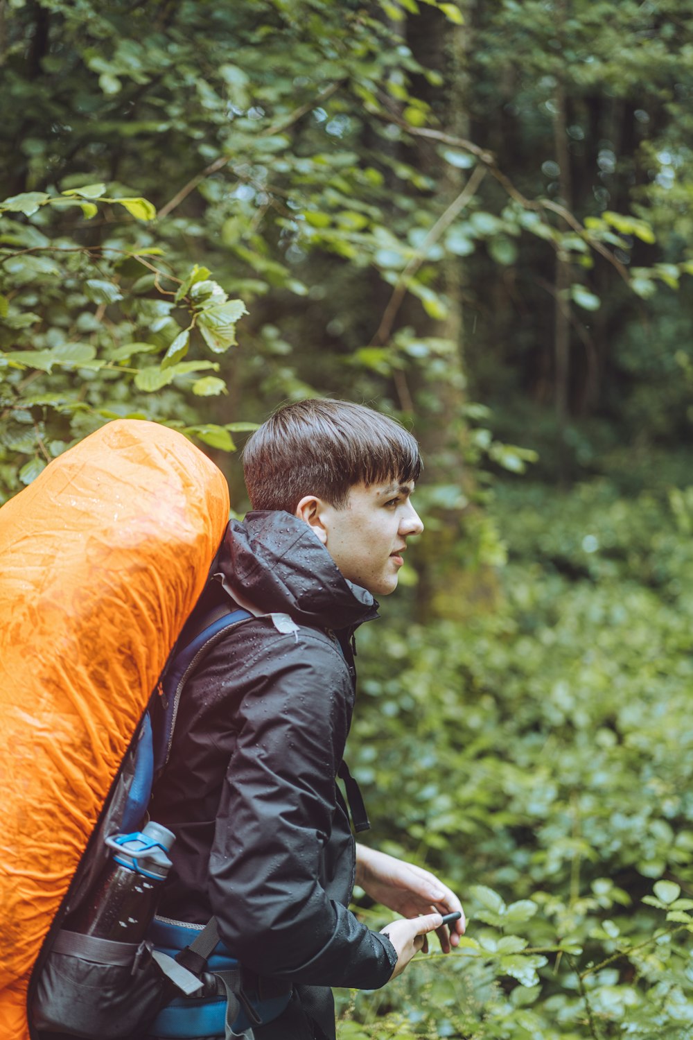 boy in black jacket sitting on orange textile