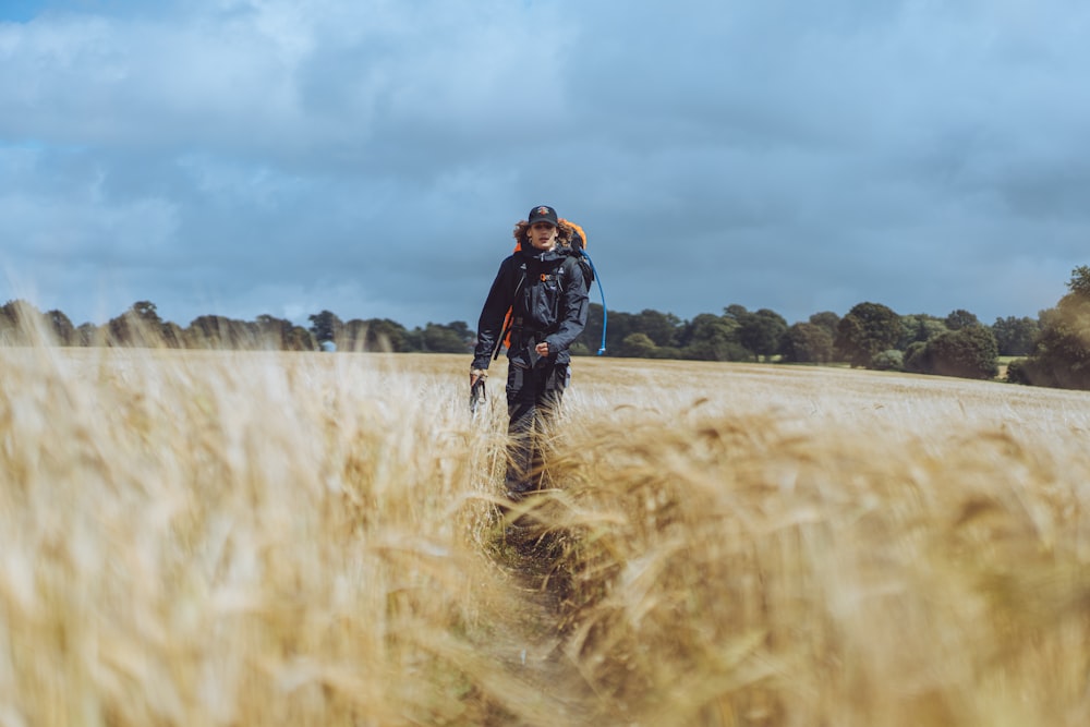 man in black jacket standing on brown grass field during daytime