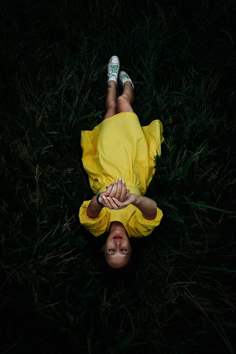 woman in yellow long sleeve shirt lying on green grass field
