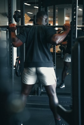 man in black tank top and white shorts holding black exercise equipment