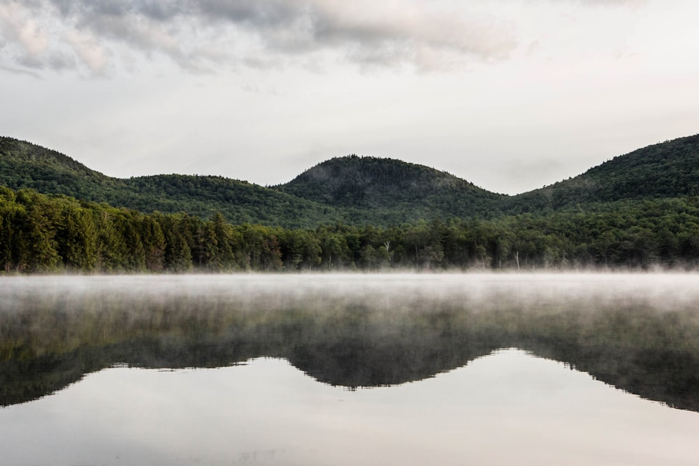 green mountain beside body of water under cloudy sky during daytime