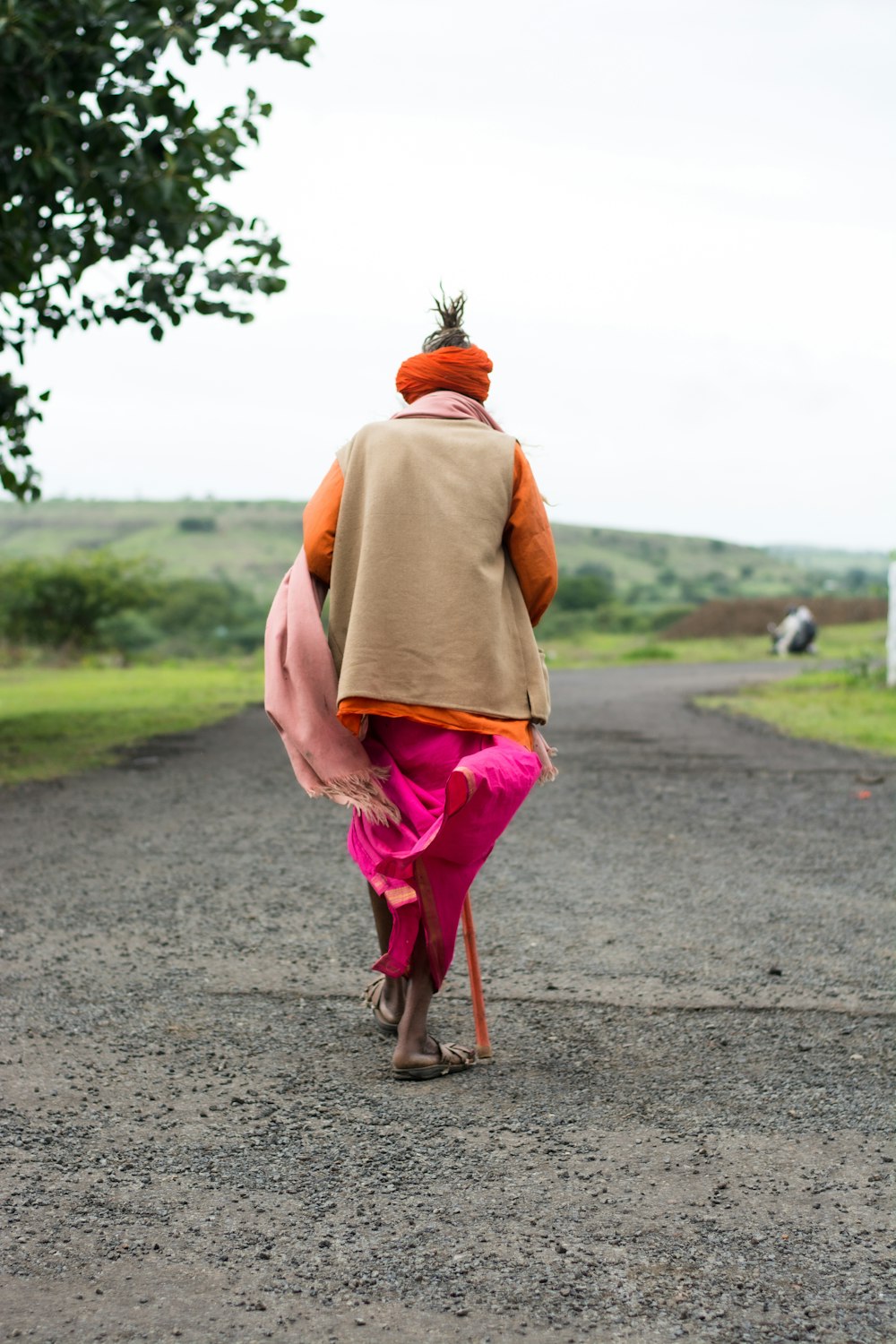 woman in pink dress walking on gray asphalt road during daytime