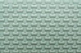 A repeating pattern of curved tiles creates a textured, three-dimensional surface. The tiles are arranged in an interlocking design with a smooth, glossy finish.