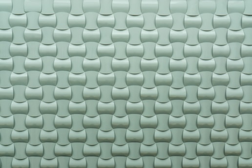 A repeating pattern of curved tiles creates a textured, three-dimensional surface. The tiles are arranged in an interlocking design with a smooth, glossy finish.