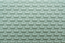 A repeating pattern of curved tiles creates a textured, three-dimensional surface. The tiles are arranged in an interlocking design with a smooth, glossy finish.