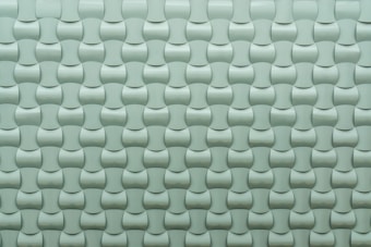 A repeating pattern of curved tiles creates a textured, three-dimensional surface. The tiles are arranged in an interlocking design with a smooth, glossy finish.