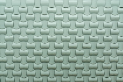 A repeating pattern of curved tiles creates a textured, three-dimensional surface. The tiles are arranged in an interlocking design with a smooth, glossy finish.