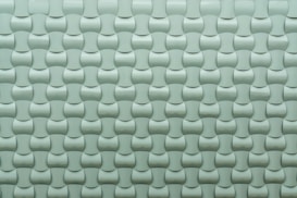 A repeating pattern of curved tiles creates a textured, three-dimensional surface. The tiles are arranged in an interlocking design with a smooth, glossy finish.