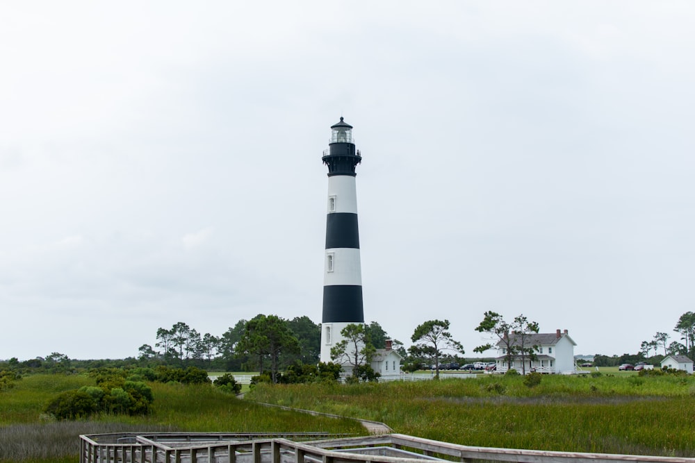 white and black lighthouse near green grass field under white sky during daytime