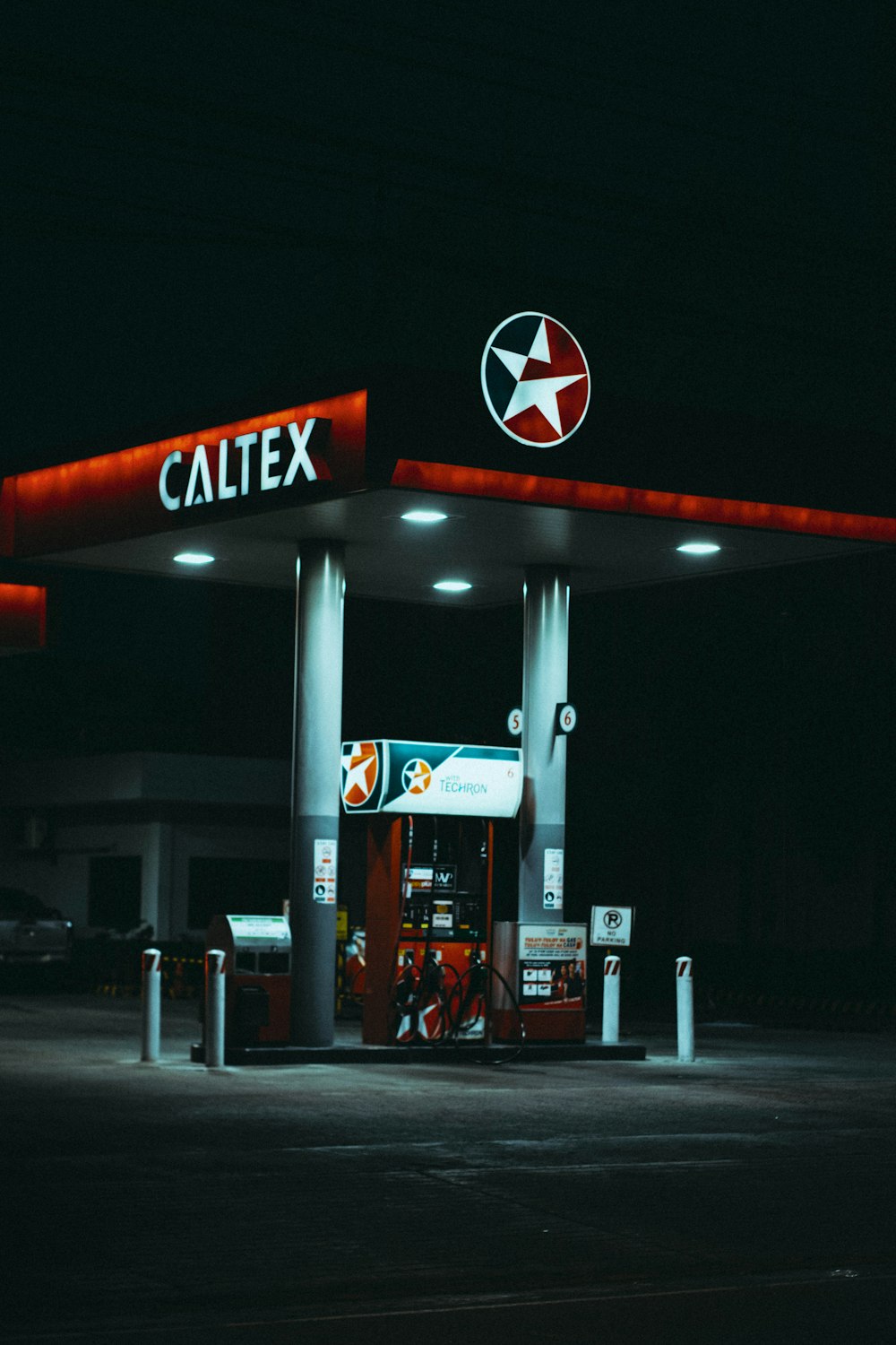 a gas station at night with a red and white sign