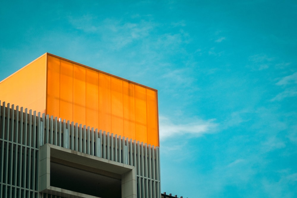 Edificio de hormigón naranja y blanco bajo el cielo azul durante el día