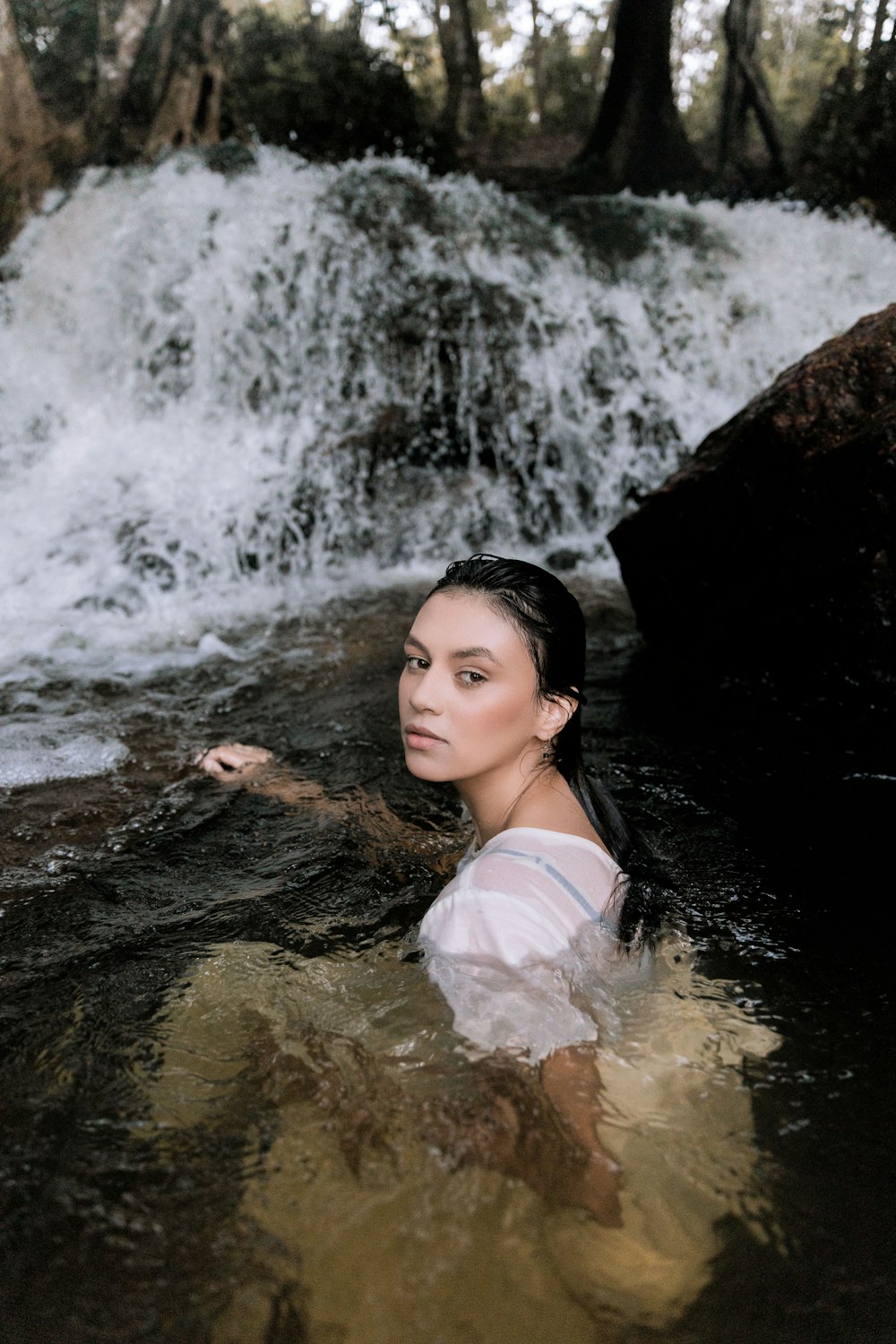 donna in canotta bianca sulle cascate d'acqua