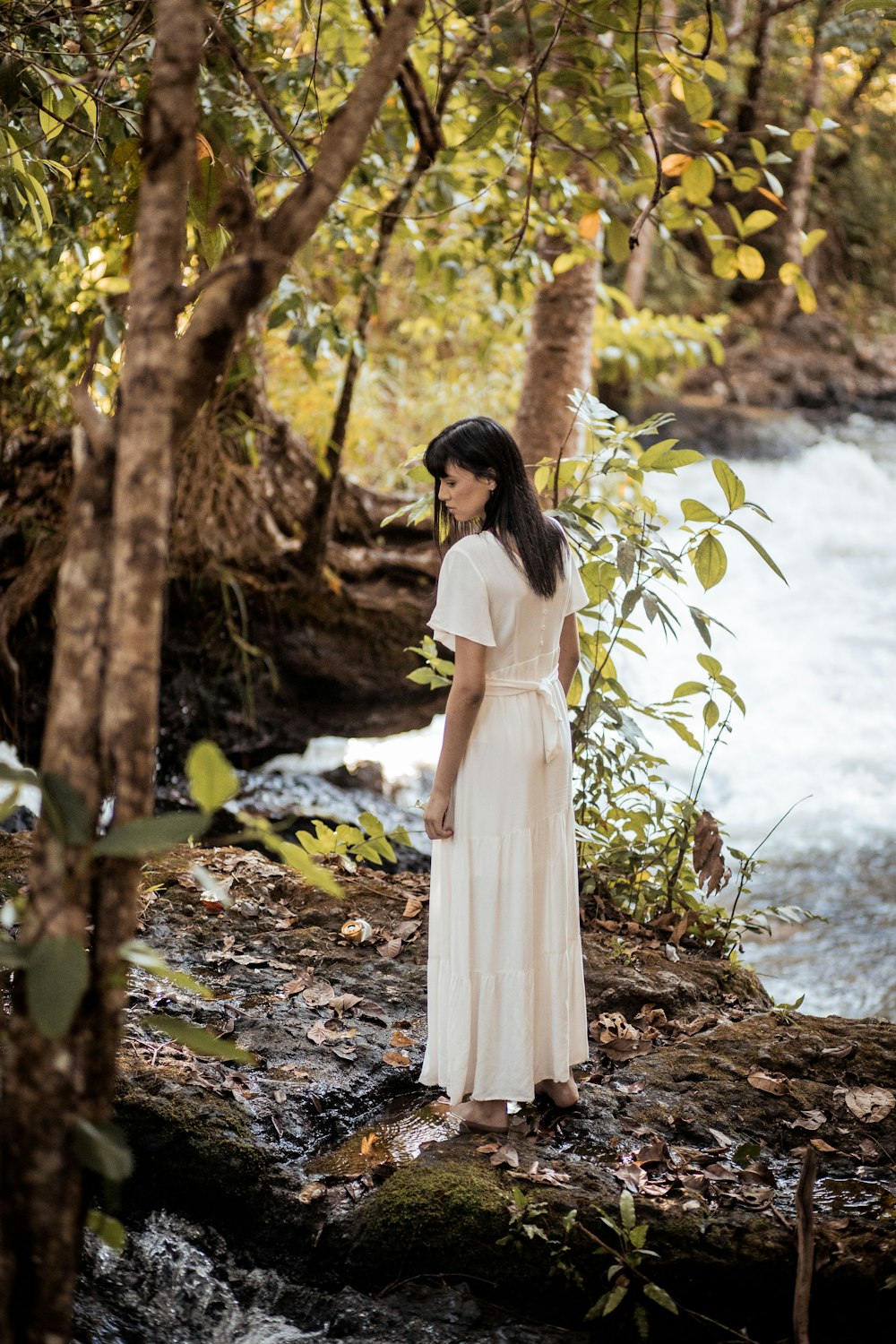 donna in vestito bianco in piedi vicino allo specchio d'acqua durante il giorno