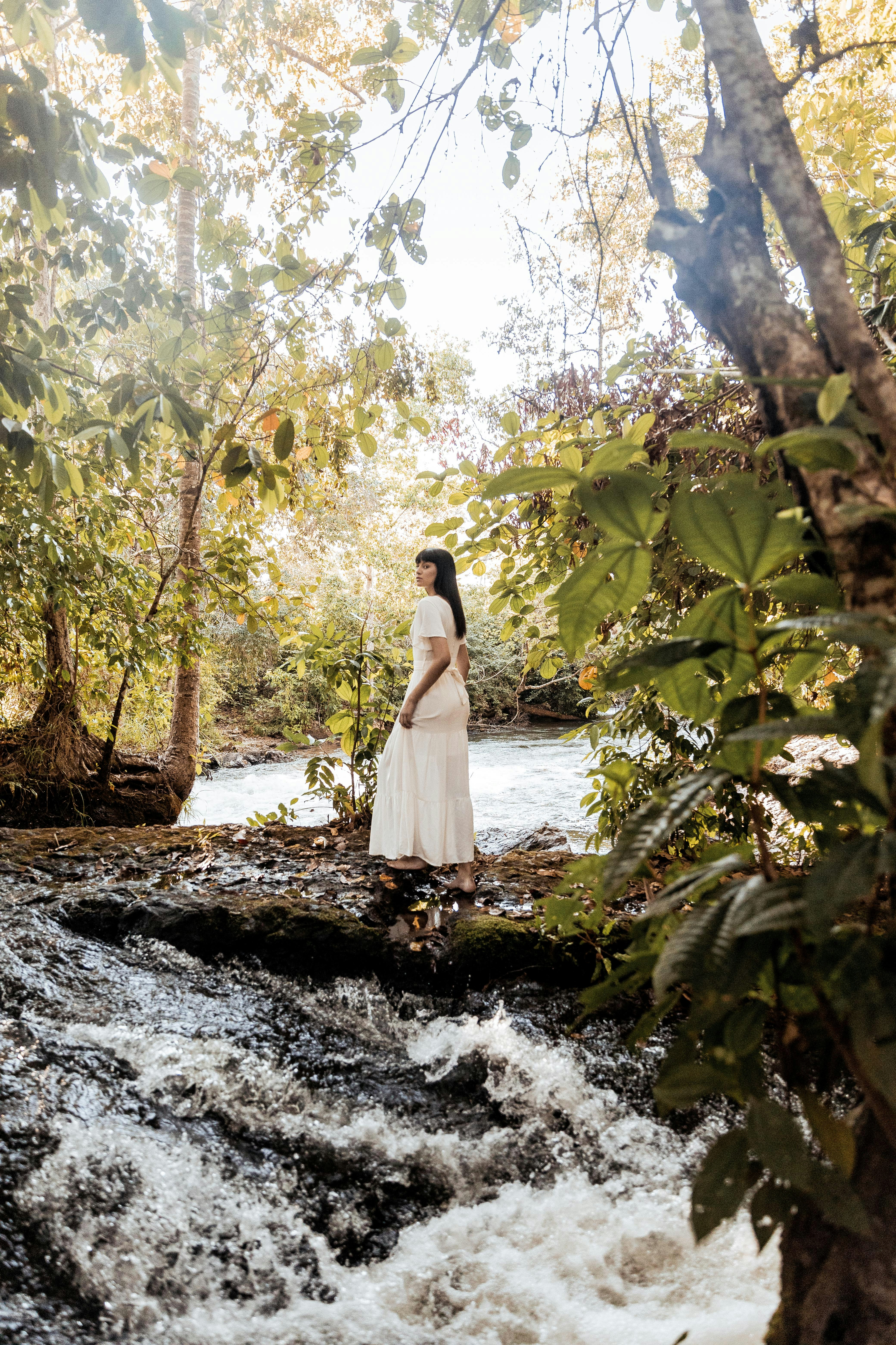 woman in white dress standing on river during daytime