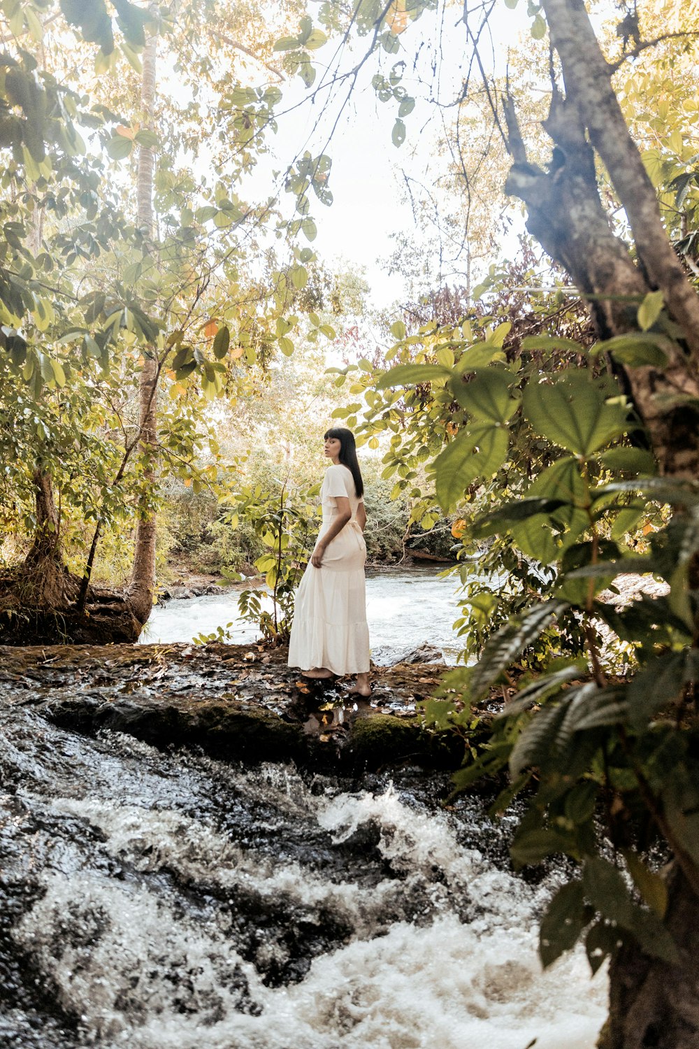 woman in white dress standing on river during daytime