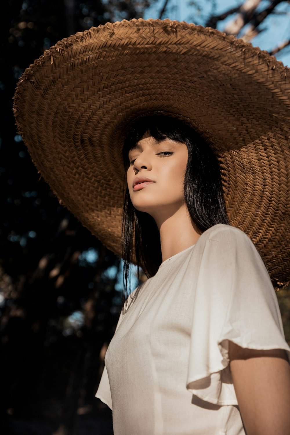 woman in white shirt wearing brown straw hat