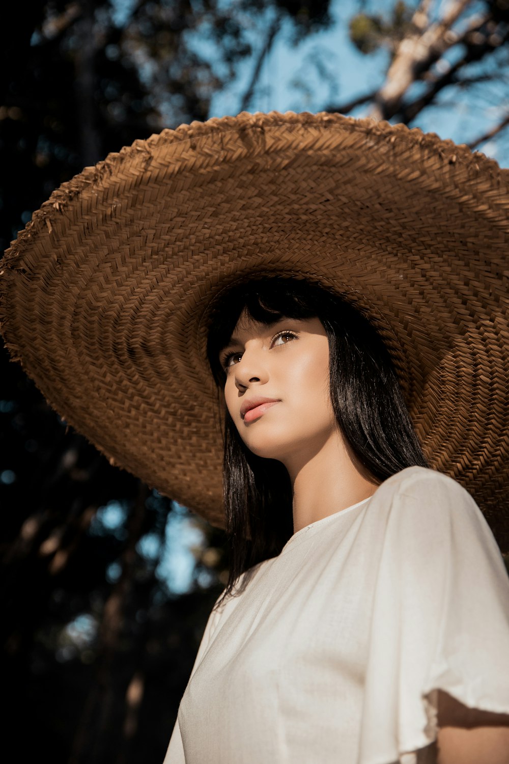 woman in white shirt wearing brown straw hat