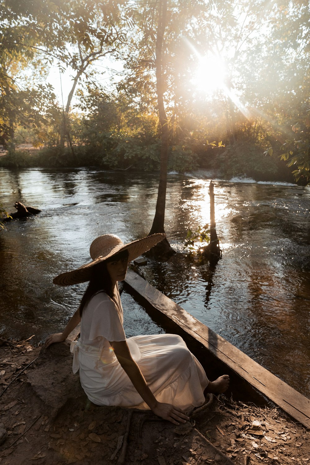 woman in white dress sitting on brown wooden boat on river during daytime