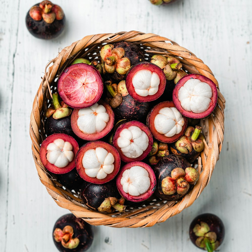 fruta redonda roja y blanca en canasta tejida marrón