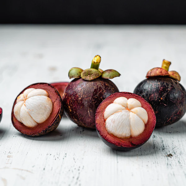 Purple mangosteen fruits cut open showing white segments