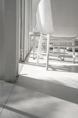 A bright, minimalistic furniture showroom with sleek chairs and tables bathed in natural light.