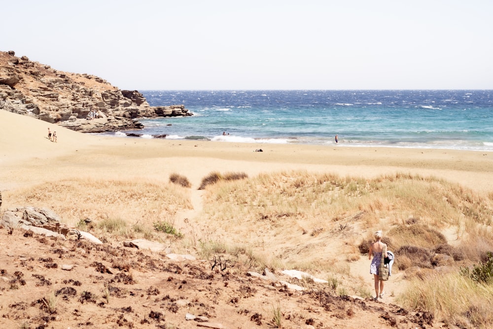 woman in white dress walking on seashore during daytime