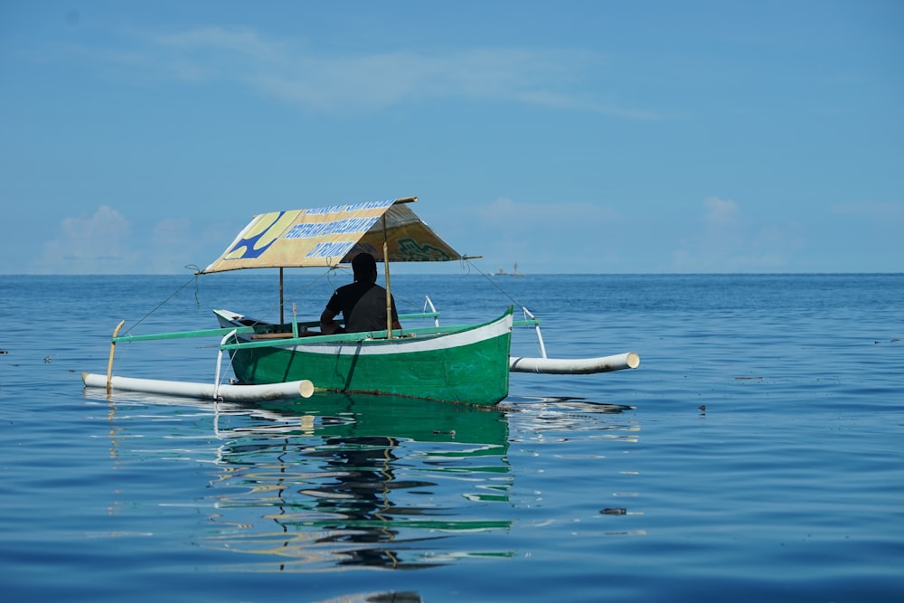person in green boat on sea during daytime