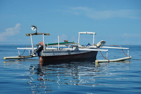 A sturdy fishing boat cutting through calm ocean waters under a clear blue sky.