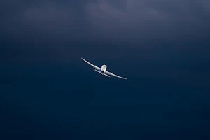 Jet airliner climbing through a deep blue evening sky