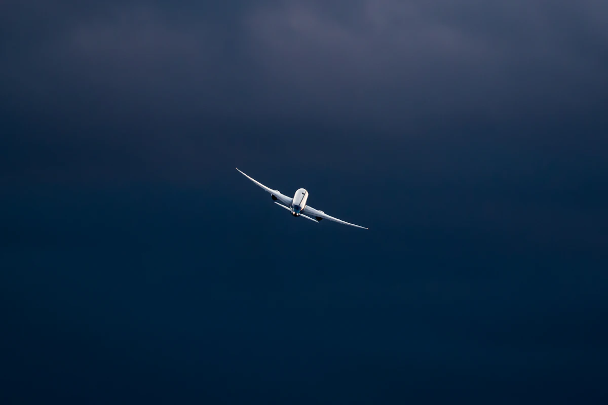 A jet airliner climbing through a deep blue evening sky