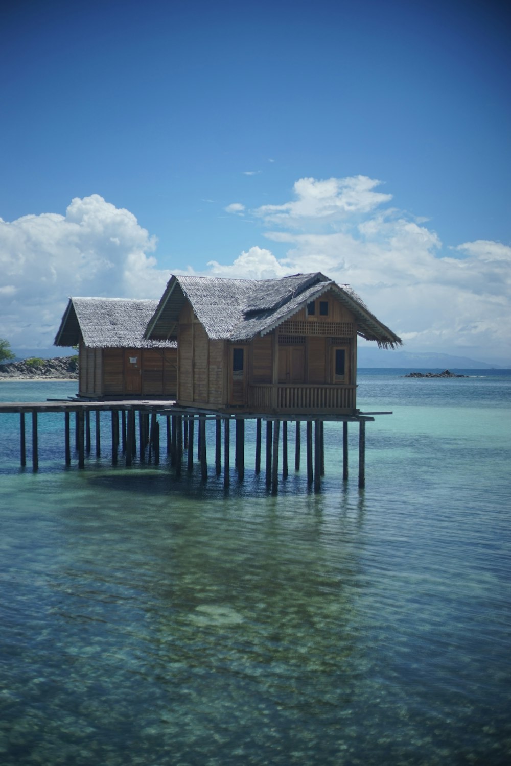 brown wooden house on sea under blue sky during daytime