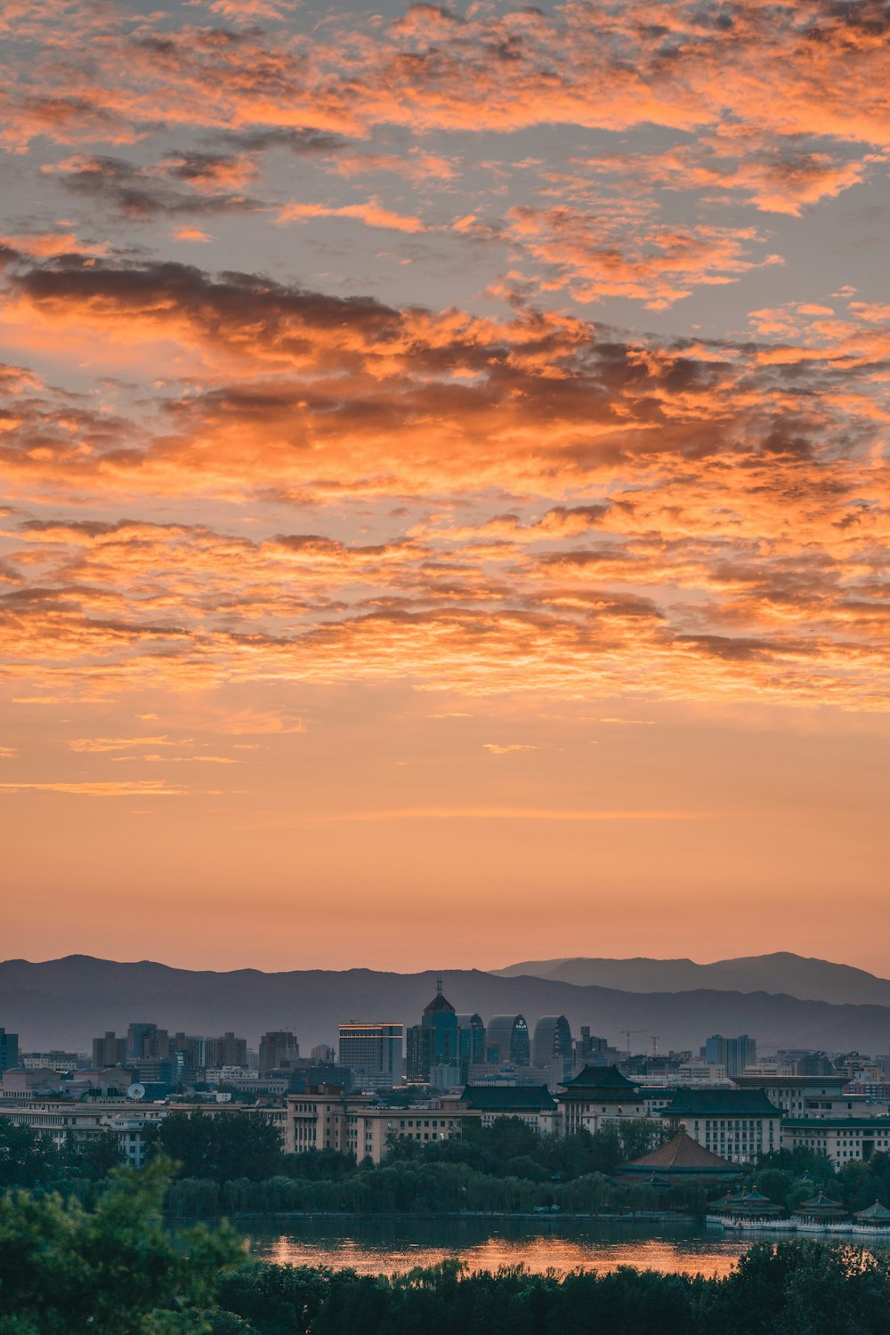 Skyline der Stadt unter orange und grau bewölktem Himmel bei Sonnenuntergang