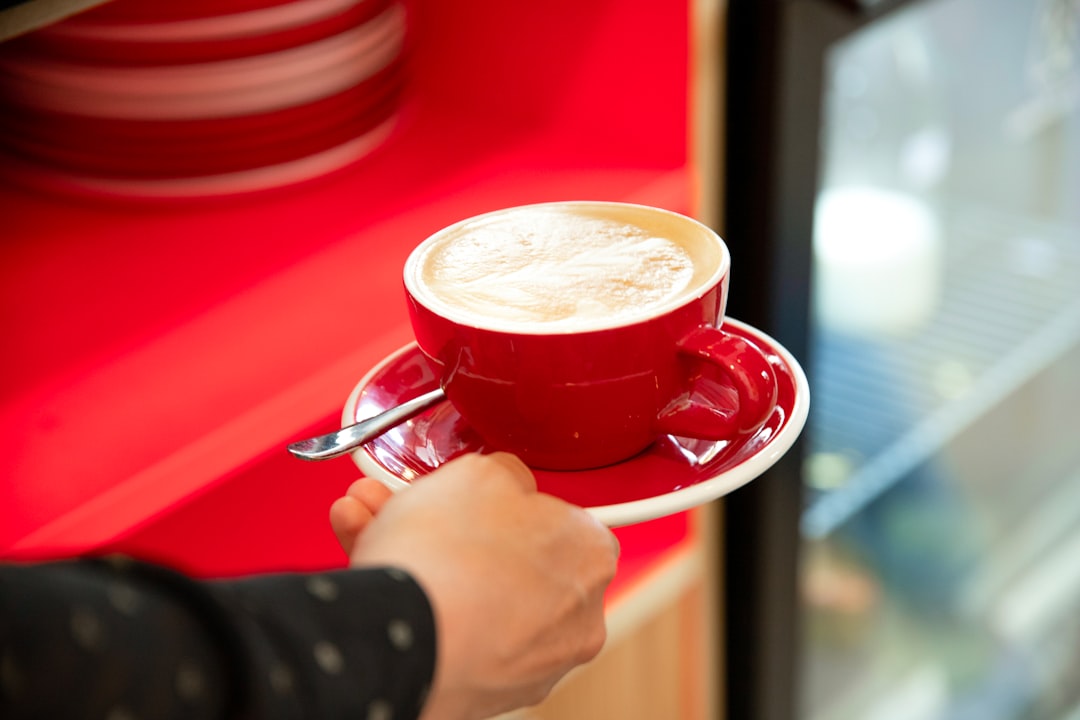 person holding red ceramic mug with coffee