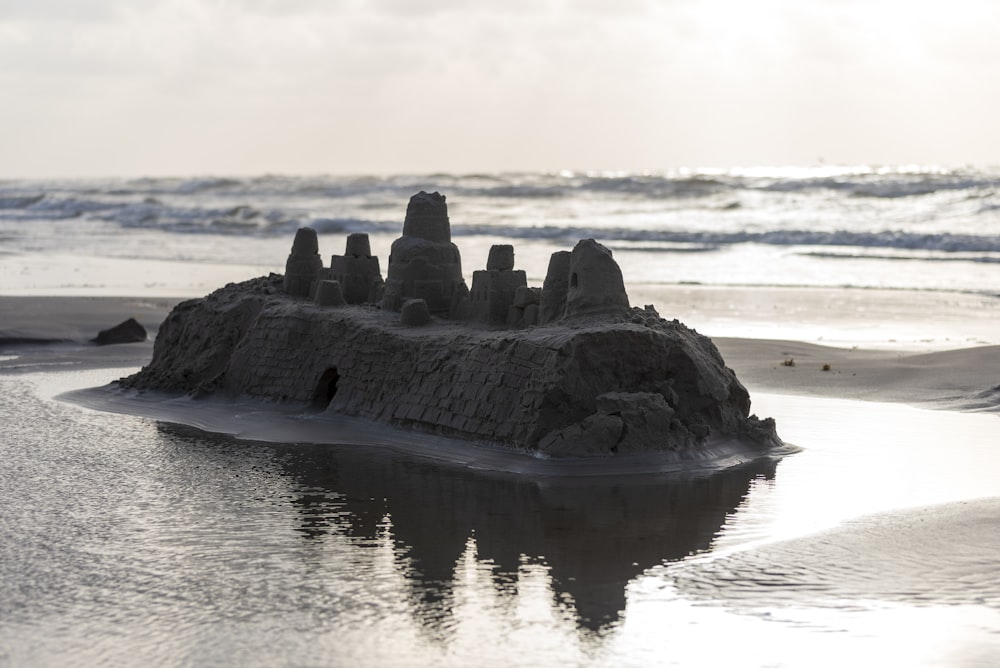 black rock formation on body of water during daytime