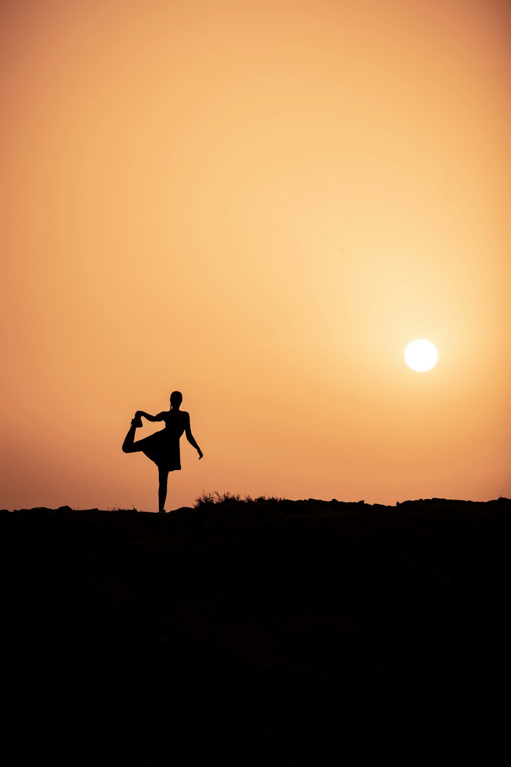 silhouette of woman standing on grass field during sunset