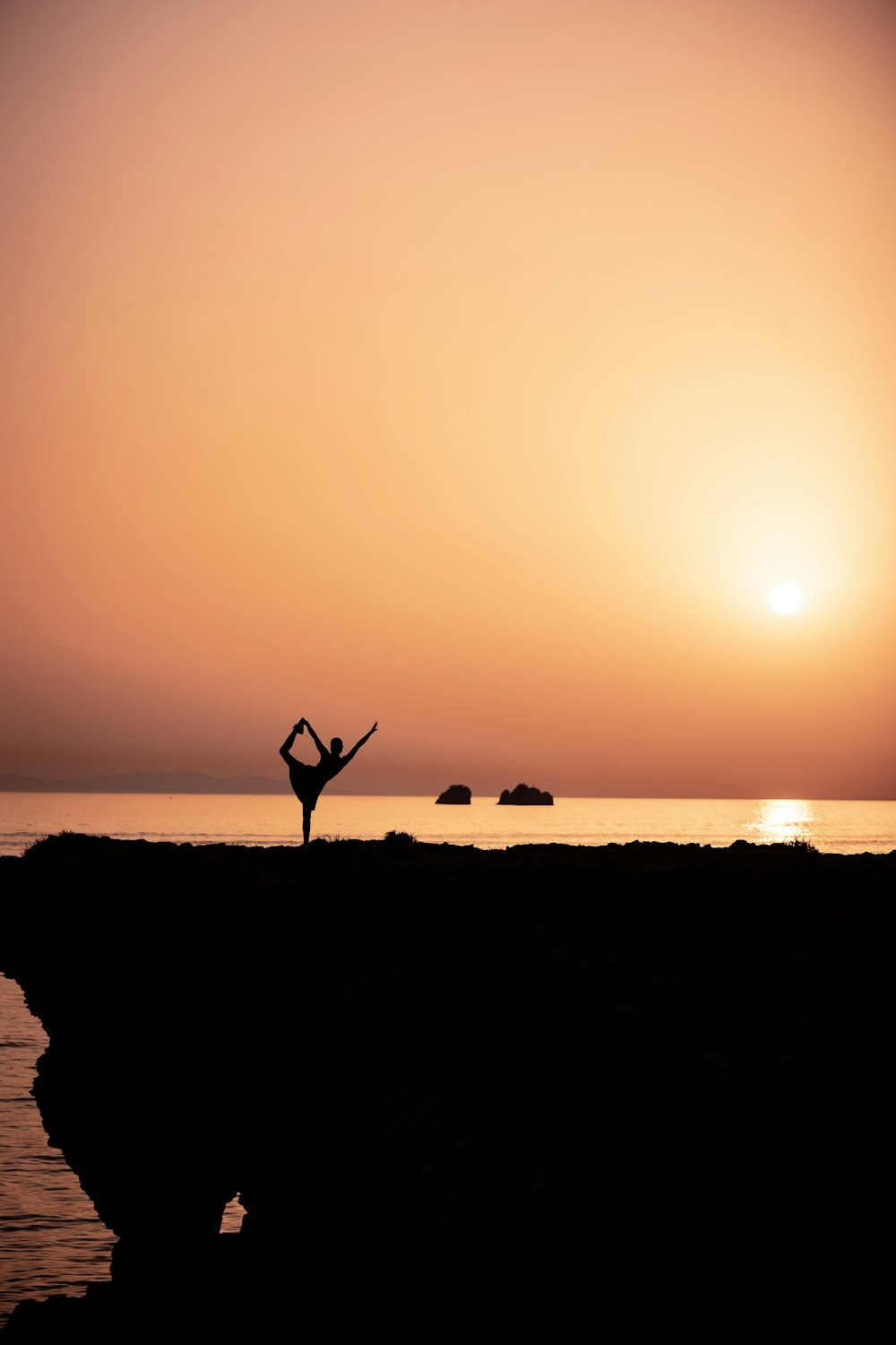 silhouette of person standing on rock formation during sunset